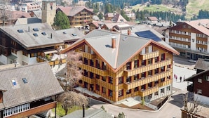 A multi-story building with a sloped roof, surrounded by other residential buildings. - Apart Hotel Adelboden am Dorfplatz Appartement/Fewo, Dusche, WC by Interhome (Adelboden)