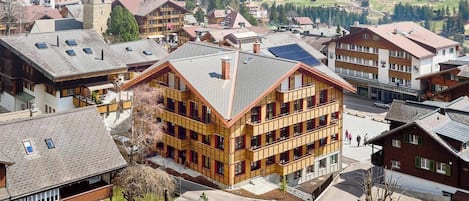 A multi-story building with a sloped roof, surrounded by other residential buildings.