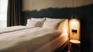 Quarto de hotel com cama, abajures e mesa de cabeceira de madeira.
