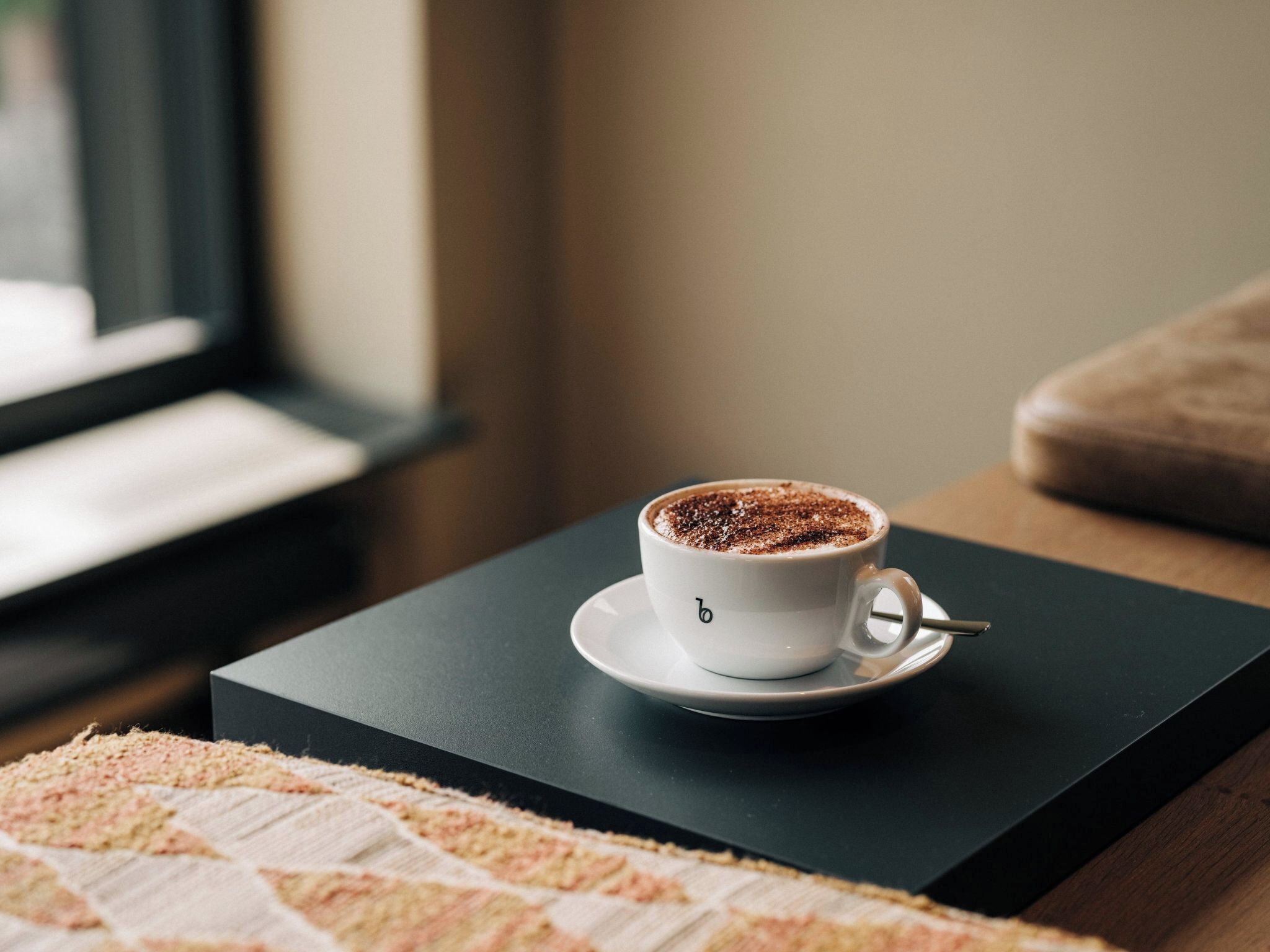 Een kop koffie op een zwarte dienblad op een houten tafel.
