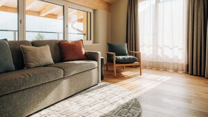 Uma sala de estar moderna com sofá, poltrona e janelas amplas.