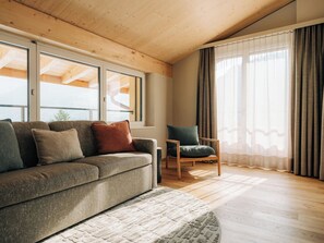 A modern living room with a sofa, chair, and large windows. - KURVE Apartments & Lounge Appartement/Fewo, Bad, WC, 2 Schlafräume by Interhome (Adelboden)