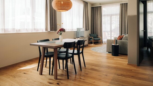 Uma sala de estar moderna com área de jantar, janelas amplas e um espaço de estar acolhedor.