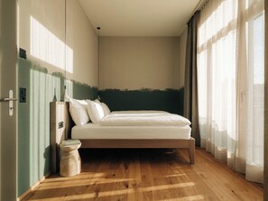 Ein Schlafzimmer mit einem Bett, Holzboden und einem Fenster mit Vorhängen.