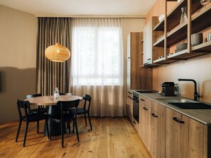 Una cucina funzionale con un tavolo da pranzo, sedie, un lampadario, una finestra con tende e mobili in legno.