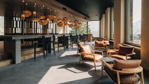 A modern bar area with high ceilings, exposed wooden beams, and a row of bar stools. - KURVE Apartments & Lounge Appartement/Fewo, Bad, WC, 2 Schlafräume by Interhome (Adelboden)