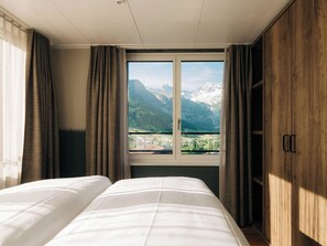 Ein Hotelzimmer mit Bett, Fenster mit Bergblick und Holzschrank.