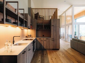 Eine moderne Küche mit Holzschränken, einem eingebauten Herd und einem großen Fenster, das für natürliches Licht sorgt.