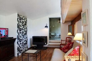 Een woonkamer met een televisie, een bank, een patroon gordijn en een stoel.