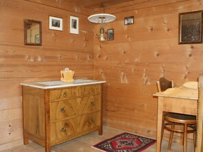 A wooden-paneled room with a wooden cabinet, a table, a chair, and a rug. - Heuzündli Ferienhaus, Dusche, WC, 3 Schlafräume 4-Zimmer-Ferienhaus by Interhome (Adelboden)