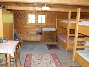 Una habitación con literas de madera, un escritorio con una silla, un aparador y una ventana.