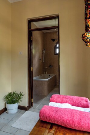 Un bagno con vasca, doccia e una pianta in vaso.
