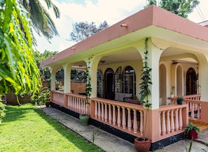 Una casa con portico coperto, finestre ad arco e piante in vaso.