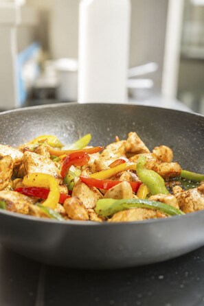 A stir-fry dish with chicken and colorful bell peppers in a pan. - Schermtanne Appartement/Fewo, Dusche oder Bad, WC, 2 Schlafräume Wohnung Nr 1 by Interhome (Adelboden)