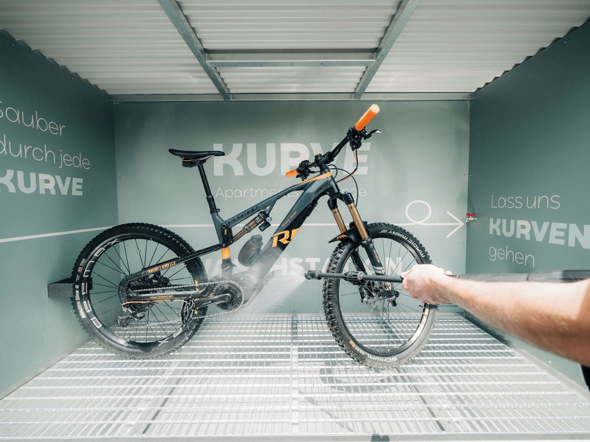 Un vélo dans une pièce dont le sol est constitué d’une grille métallique et les murs sont recouverts de texte.