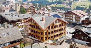 Ein mehrstöckiges Gebäude mit geneigtem Dach, umgeben von anderen Wohnhäusern.