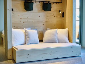 Ein hölzernes Bett mit weißer Bettwäsche und zwei hängenden Taschen.