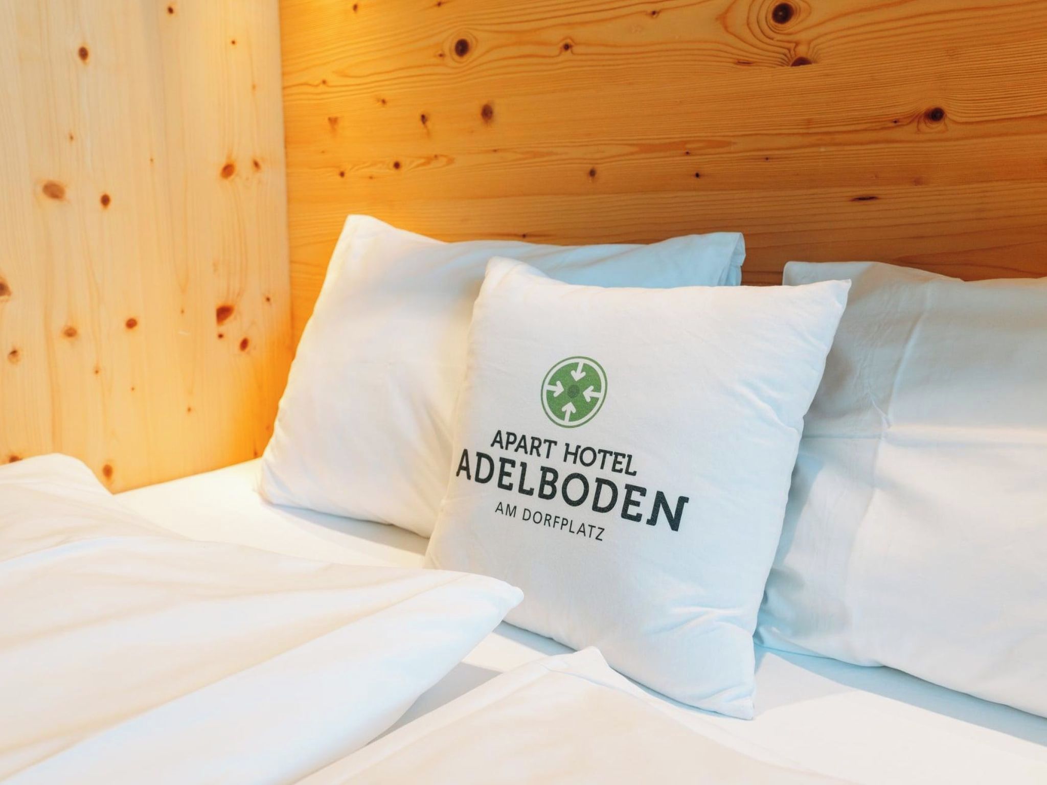Une chambre d’hôtel avec une tête de lit en bois et du linge de lit blanc.