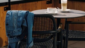 A table with a glass of beer and a cup, a denim jacket on a chair, and a view of a hilly landscape. - KURVE Apartments & Lounge Studio, Bad, WC, 1 Schlafraum by Interhome (Adelboden)