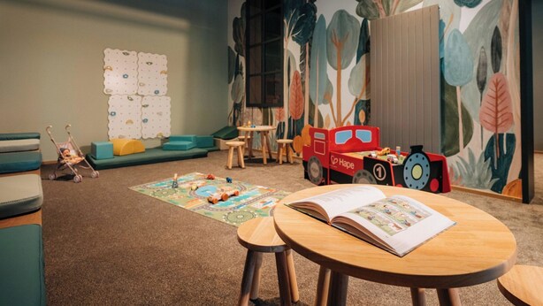 A children's playroom with a large wall mural, a play mat, a red toy truck, and a book on a table. - KURVE Apartments & Lounge Studio, Bad, WC, 1 Schlafraum by Interhome (Adelboden)