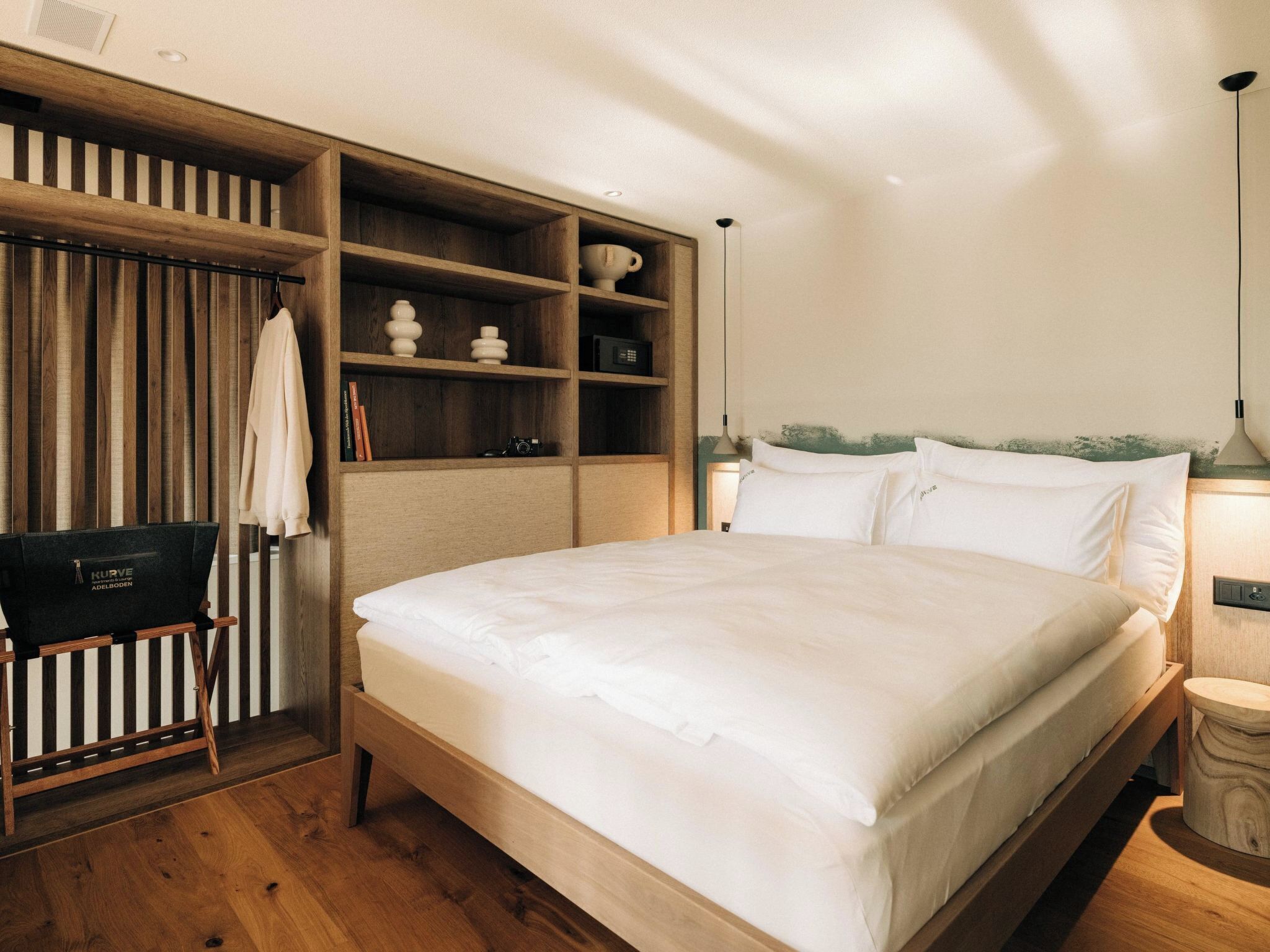 Een slaapkamer met een houten bed, een inbouwkast, een tafeltje en een lamp.