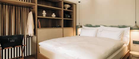 Een slaapkamer met een houten bed, een inbouwkast, een tafeltje en een lamp.