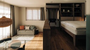 A compact hotel room with a bed, a sofa, a small table with glasses, and a wardrobe. - KURVE Apartments & Lounge Studio, Bad, WC, 1 Schlafraum by Interhome (Adelboden)