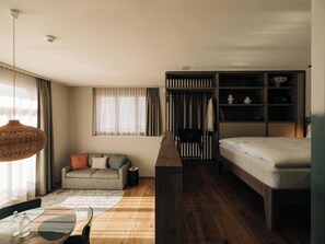 Ein kleines Hotelzimmer mit einem Bett, einer Schlafcouch, einem Tisch mit Gläsern und einem Kleiderschrank.