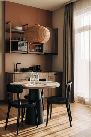 A modern kitchen with a round dining table, two chairs, a hanging light fixture, and wooden cabinets. - KURVE Apartments & Lounge Studio, Bad, WC, 1 Schlafraum by Interhome (Adelboden)