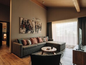 Un salon moderne avec un canapé d’angle, une table basse et un grand tableau abstrait accroché au mur.