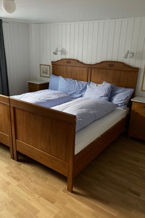 Ein hölzernes Bett mit Kopfteil, Nachttisch und Beistelltisch.