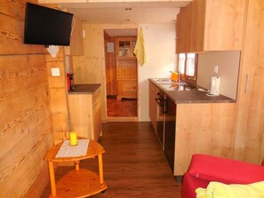 A compact kitchen with wooden cabinets, a small table with a candle, and a red sofa. - Sunneweg Appartement/Fewo, Dusche, WC, 1 Schlafraum 2-Zimmerwohnung by Interhome (Adelboden)