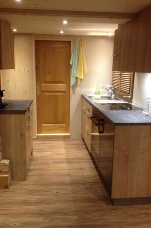 A compact kitchen with wooden cabinets, a sink, and a countertop. - Sunneweg Appartement/Fewo, Dusche, WC, 1 Schlafraum 2-Zimmerwohnung by Interhome (Adelboden)