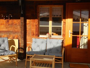 A wooden cabin with a window, a door, and two chairs with patterned cushions. - Sunneweg Appartement/Fewo, Dusche, WC, 1 Schlafraum 2-Zimmerwohnung by Interhome (Adelboden)