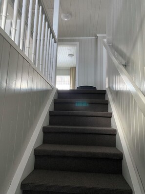 Eine Treppe mit Geländer und Blick auf einen Raum mit Fenster und Vorhängen.
