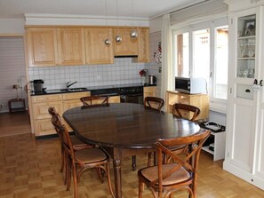 A kitchen with wooden cabinets, a round dining table, and chairs. - Lavendel AP B22 Appartement/Fewo, Bad, WC, 3 Schlafräume 4-Zimmerwohnung by Interhome (Adelboden)