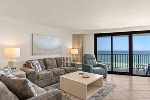 Een moderne woonkamer met een bank, fauteuils, een salontafel en een groot raam met uitzicht op de oceaan.