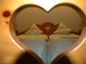 A heart-shaped window framing a bed with pillows and a headboard. - Bärgchutzli Parterre Appartement/Fewo, Dusche, WC, 1 Schlafraum by Interhome (Adelboden)