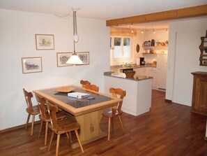 A dining area with a wooden table and chairs, a kitchen in the background, and framed pictures on the wall. - Chalet Bim Stei Appartement/Fewo, Bad, WC, 2 Schlafräume 3-Zimmerwohnung by Interhome (Adelboden)
