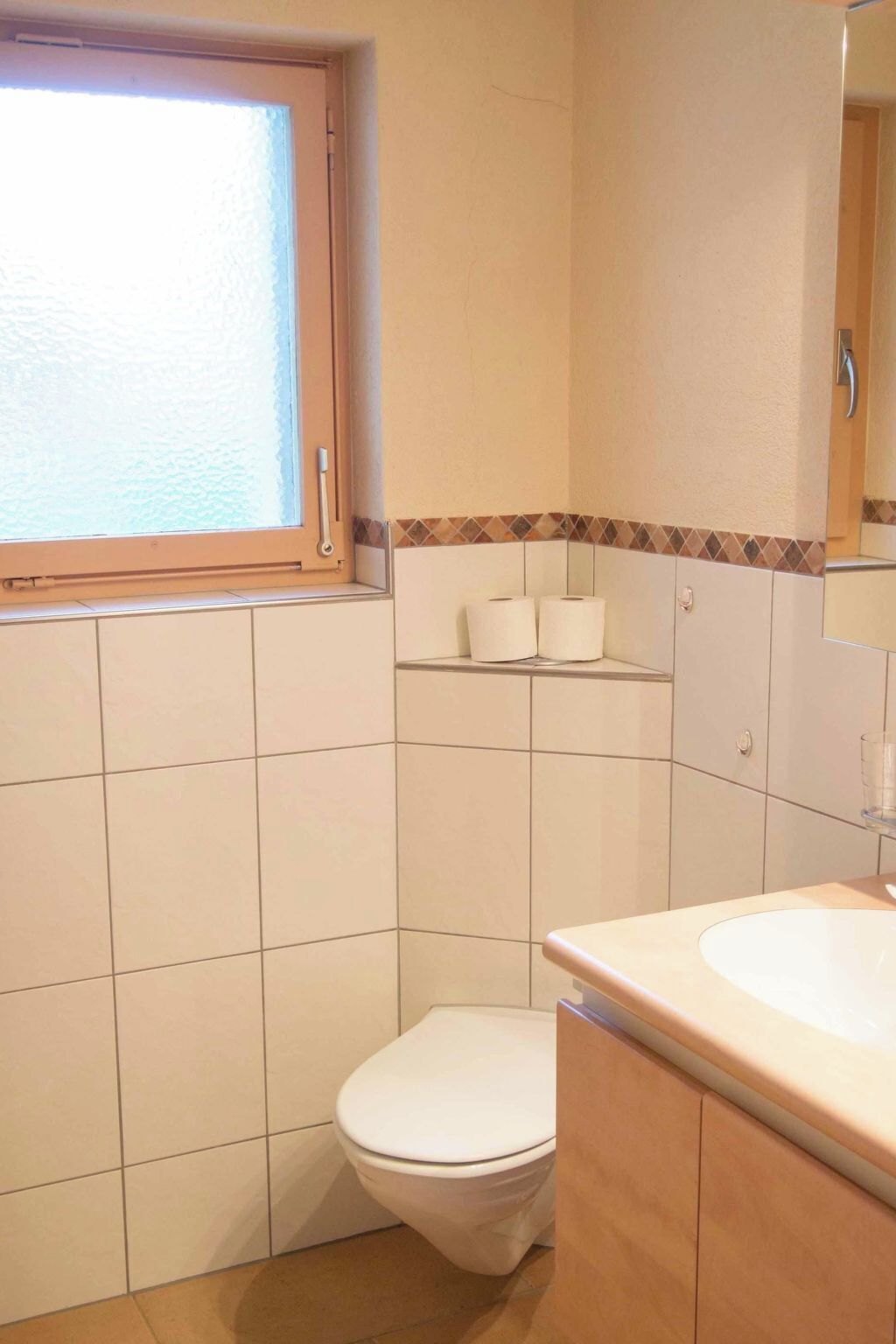 Et badeværelse med toilet, håndvask og et vindue.