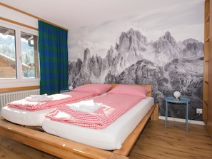 A bedroom with a bed, a window, a curtain, and a wall mural of mountains. - Baldrian C14 Appartement/Fewo, Bad, WC, 3 Schlafräume 4.5- Zimmerwohnung by Interhome (Adelboden)