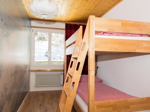 A bunk bed room with a wooden ladder, a radiator, and a window with a view of trees. - Baldrian C14 Appartement/Fewo, Bad, WC, 3 Schlafräume 4.5- Zimmerwohnung by Interhome (Adelboden)