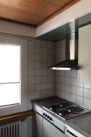 A kitchen with a stove, a range hood, and patterned tiles. - Akalei Appartement/Fewo, Dusche, WC, 3 Schlafräume 4.5-Zimmerwohnung by Interhome (Adelboden)