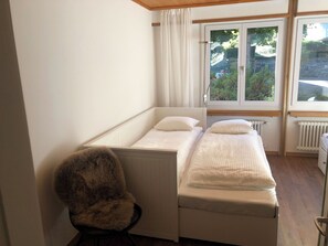 A small room with a single bed, a chair, and a window with a view of greenery. - Akalei Appartement/Fewo, Dusche, WC, 3 Schlafräume 4.5-Zimmerwohnung by Interhome (Adelboden)