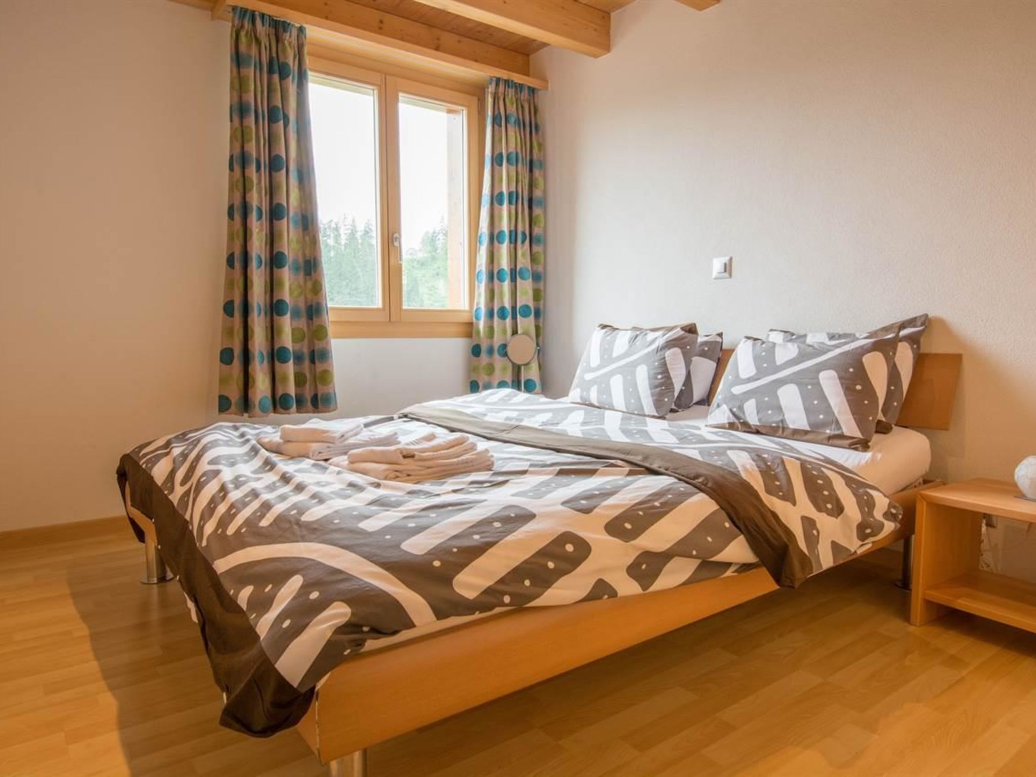 Ein Schlafzimmer mit Bett, Vorhängen, einem Nachttisch und einem Fenster.