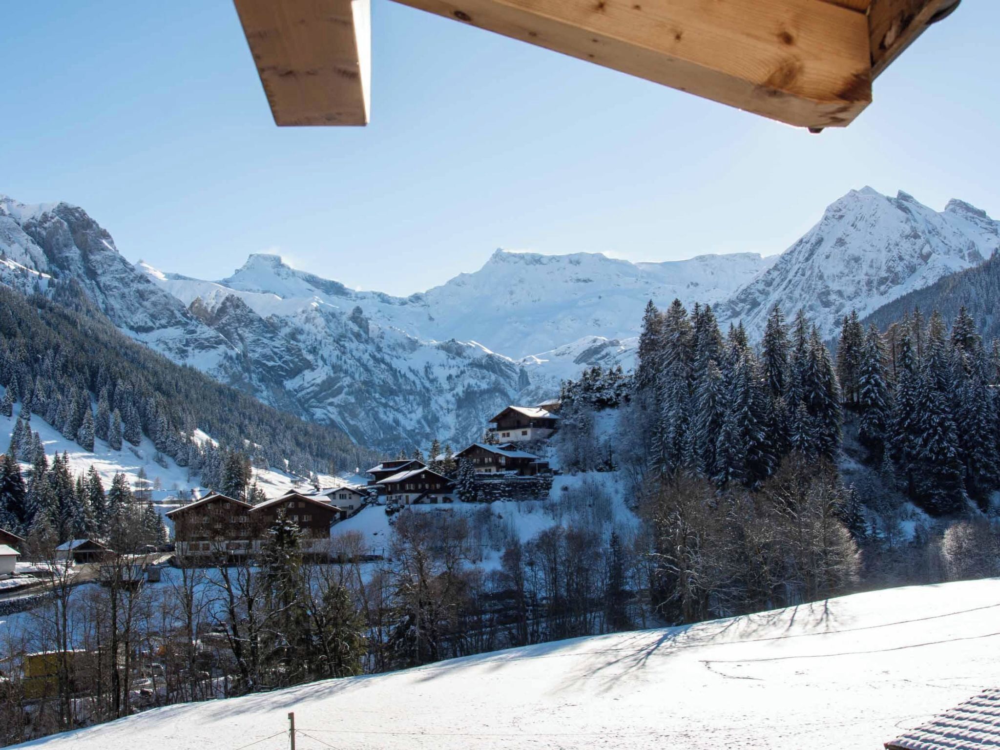 A mountainous landscape with snow-covered peaks and a cluster of wooden chalets.