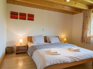 A bedroom with a wooden bed, two bedside tables, a lamp on each, a red abstract painting on the wall, and a window with curtains. - Schützenrain DG Appartement/Fewo, Dusche und Bad, WC, 4 oder mehr Schlafräume by Interhome (Adelboden)