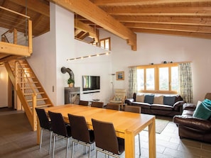 A spacious living area with a wooden staircase, a dining table with chairs, a sofa, and a television. - Schützenrain DG Appartement/Fewo, Dusche und Bad, WC, 4 oder mehr Schlafräume by Interhome (Adelboden)