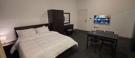 Hotellihuone, jossa on sänky, televisio, työpöytä ja tuoli.