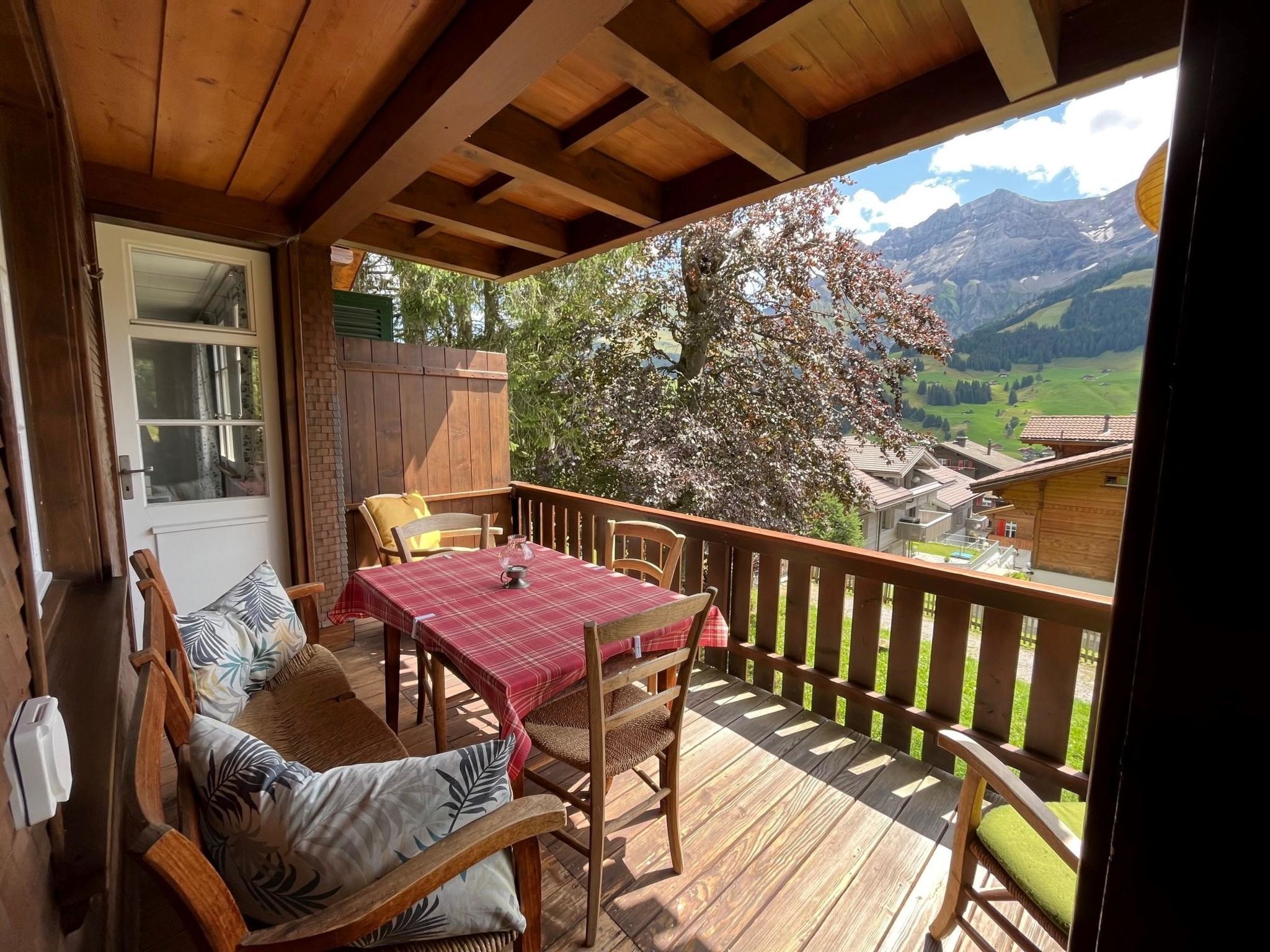 A wooden deck with a table and chairs, overlooking a mountainous landscape.